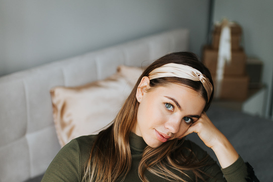 Stylish girl in white suite wearing sunglasses and beige silk headband, holding a wine glass