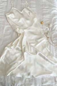 White silk dress lying on a bed