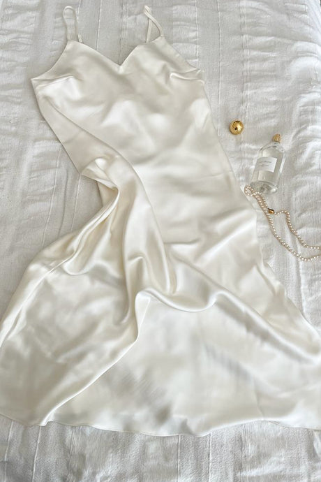 White silk dress lying on a bed