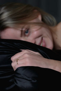 A girl behind black silk pillowcase, smiling and looking into the camera