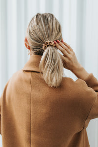 Blond girl from the back with gold silk scrunchie in her ponytail