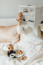 Load image into Gallery viewer, Girl in bed with Cappuccino Beige natural silk pillowcases reading a newspaper
