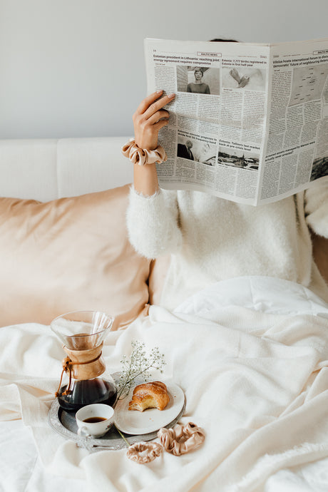Girl in bed with Cappuccino Beige natural silk pillowcases reading a newspaper