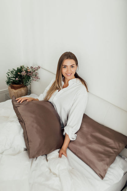 Smiling girl resting in bed with two mocha colour pillowcases